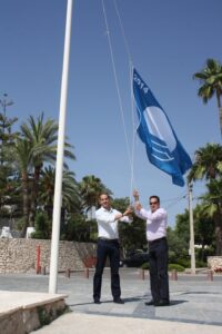 Juan Bautista Roselló i Arturo Poquet hissen la bandera blava a la platja de la Fustera